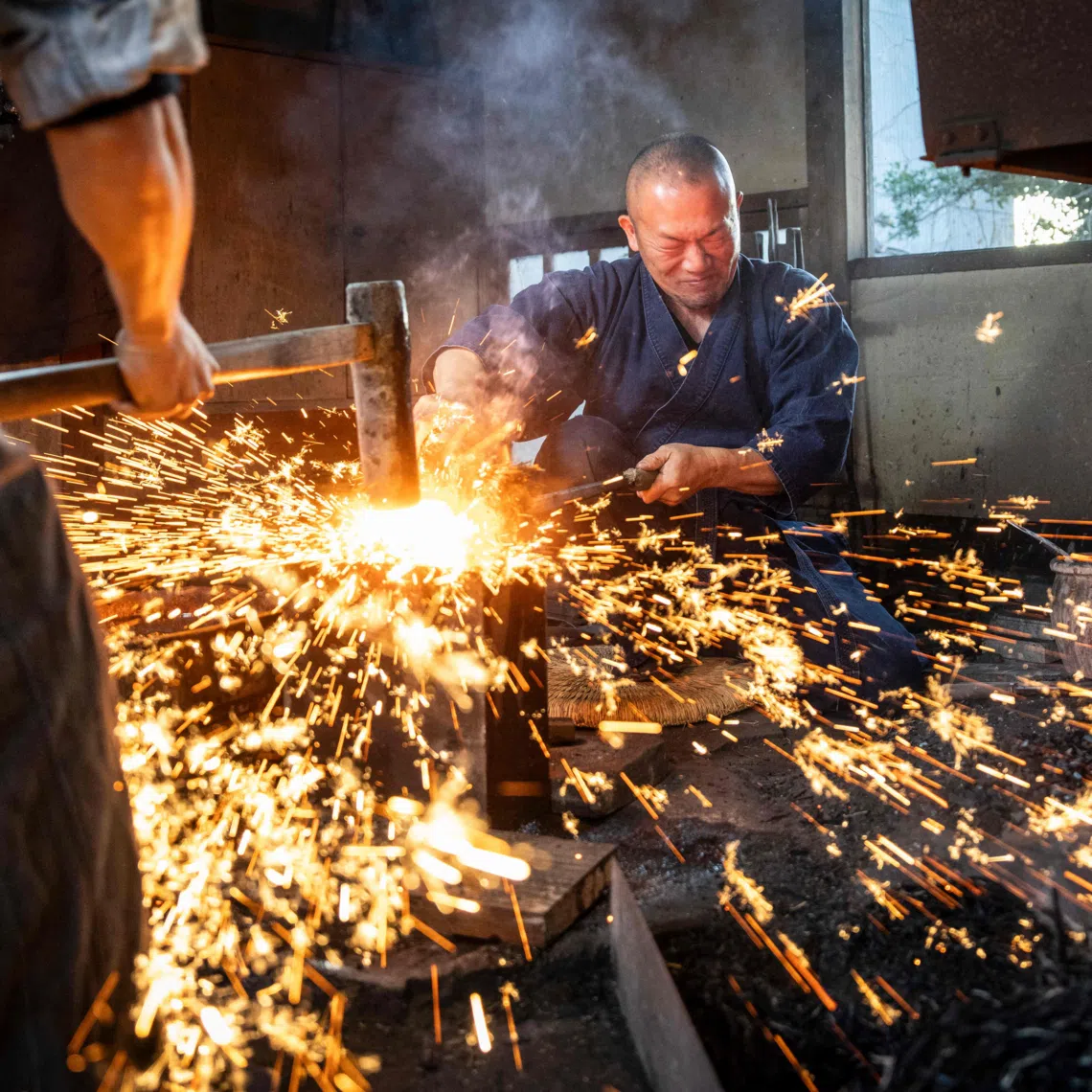 Swordsmith Akihira Kawasaki (R) steadies steel over an anvil while his apprentice hammers the metal to forge katana blades on Jan 9 in Japan.