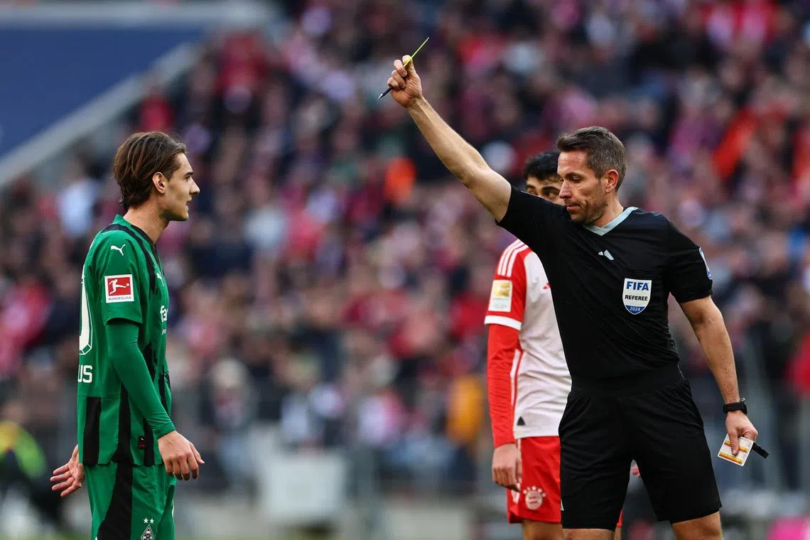Referee Tobias Stieler showing Borussia Moenchengladbach's Florian Neuhaus a yellow card during a Bundesliga match also involving Bayern Munich  on Feb 3.