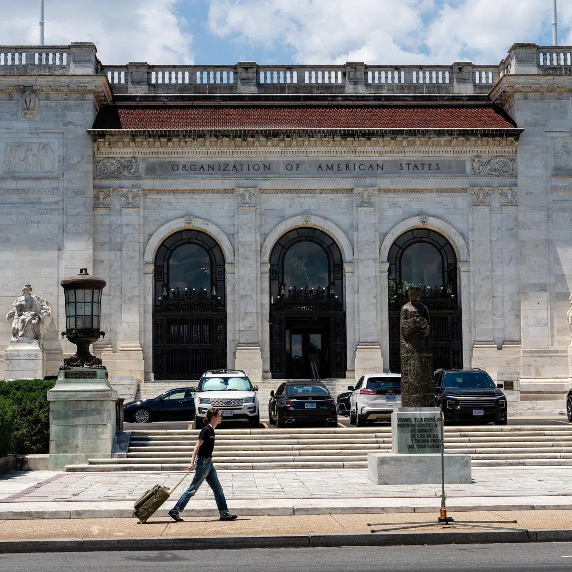 A person pulls a rolling suitcase as they walk by the Organization of American States (OAS) headquarters in Washington, D.C., U.S., June 17, 2026. REUTERS/Eric Lee