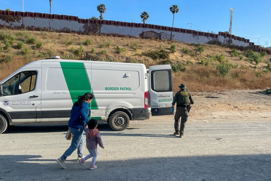 A U.S. Border Patrol agent leads Jessica Leon of Ecuador and her 3-year-old daughter onto a van to be processed in San Diego, California, U.S. June 4, 2024. REUTERS/Daniel Trotta