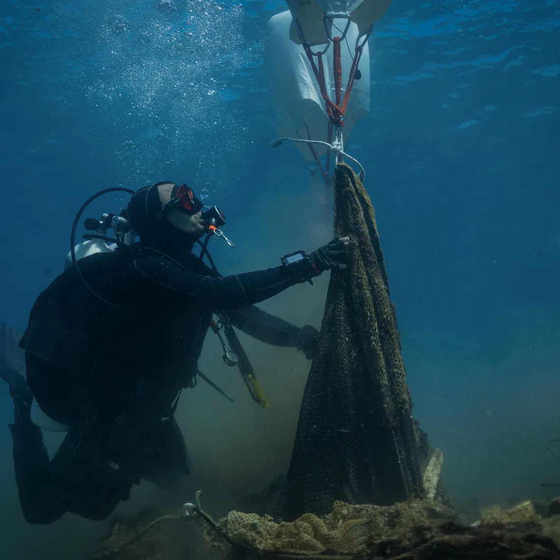Volunteer divers from the environmental group Aegean Rebreath use lift bags to raise a fish-farming net from the seabed during an underwater cleanup off the islet of Sapientza, near Methoni, in southern Greece, October 11, 2025. REUTERS/Stelios Misinas