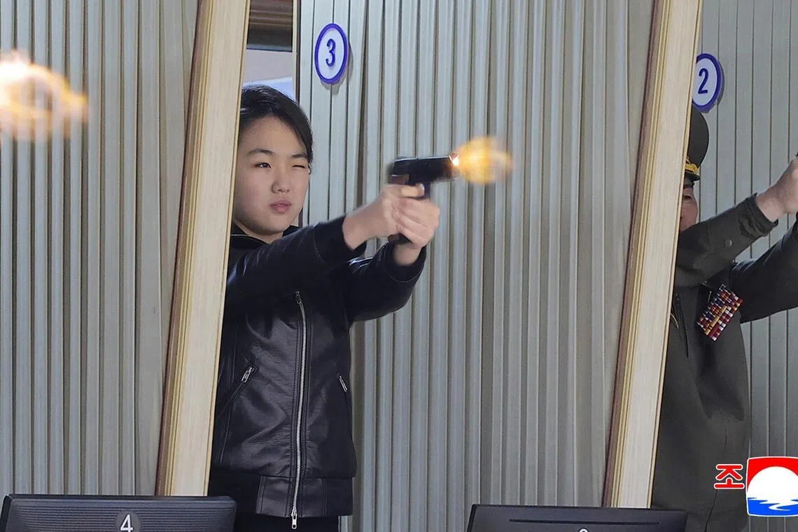 North Korean leader Kim Jong Un's daughter Kim Ju Ae (centre) test firing a new-type pistol during an inspection of a major munitions factory.