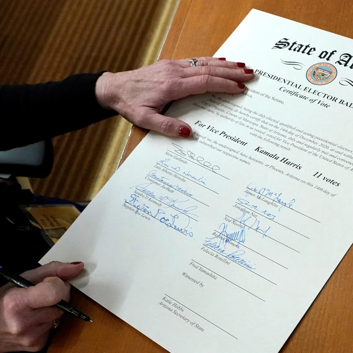 FILE PHOTO: A member of Arizona's Electoral College signs the Arizona Presidential Elector Ballot certificate in Phoenix, Arizona, U.S. December 14, 2020. Ross D. Franklin/Pool via REUTERS/File Photo