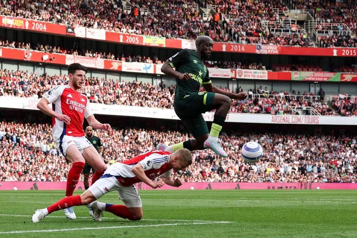 Arsenal defender Oleksandr Zinchenko (centre) heads the ball as Brentford striker Yoane Wissa jumps to control it, next to Arsenal midfielder Declan Rice.