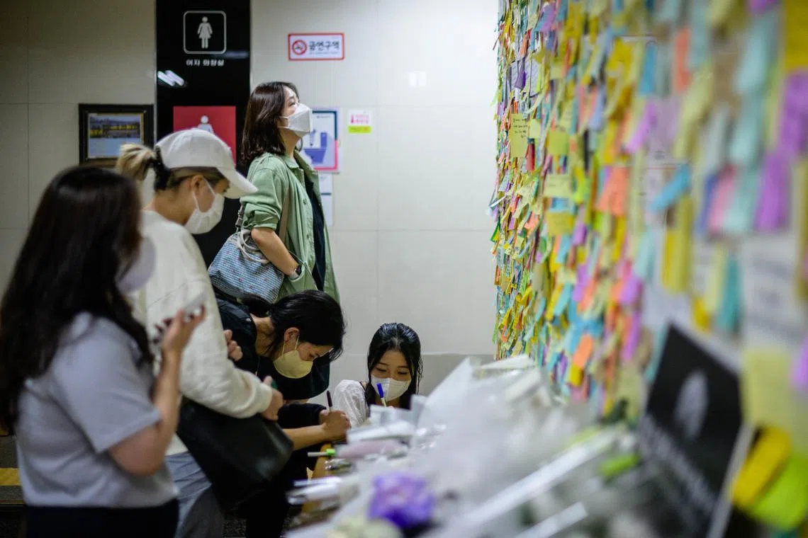 Women pay their respects to the victim with handwritten notes near the entrance to a female lavatory at Sindang Station in Seoul, on Sept 19, 2022.