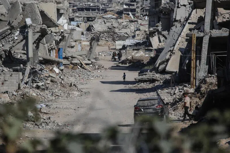 Palestinians making their way through destroyed buildings in Khan Younis in the southern Gaza Strip.