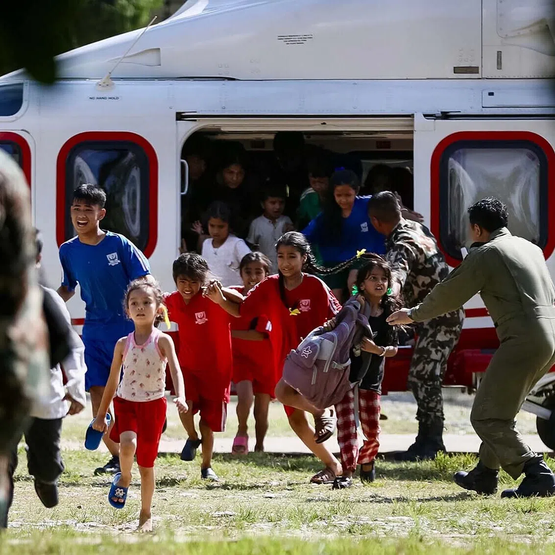 Rescued children disembark from a helicopter at an army camp following flash floods, in Battar Bazar town in Nepal's Nuwakot district on August 28, 2026. Devastating floods on the Nepal-Tibet border region have killed at least 469 people, Nepali police said on August 28, 48 hours after the disaster. (Photo by PRABIN RANABHAT / AFP)