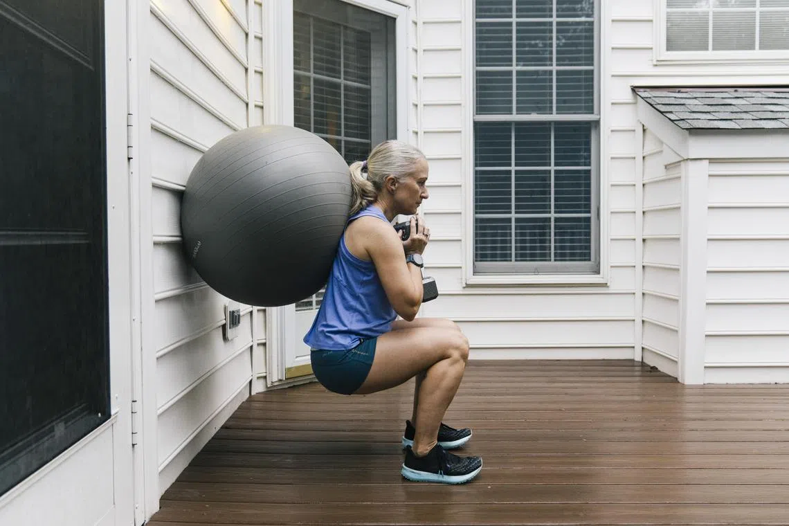 Alison Gittelman, an experienced marathoner and triathlete, uses a weight with an exercise at her home in Chantilly, Va., Aug. 8, 2024. Gittelman incorporated more strength training into her exercise routine once she entered menopause. (Lexey Swall/The New York Times)