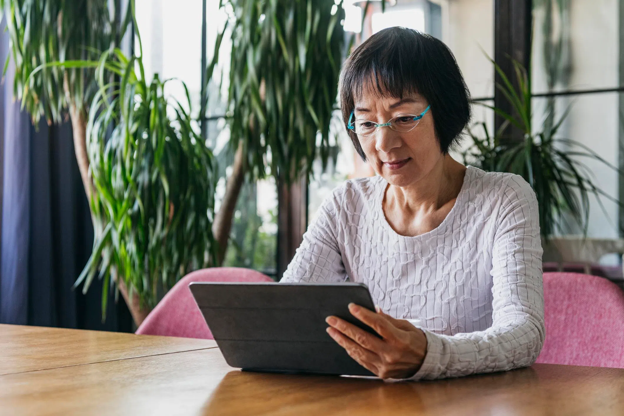 Kobo or Kindle: Elderly Chinese woman in her sitting at the table with an e-reader