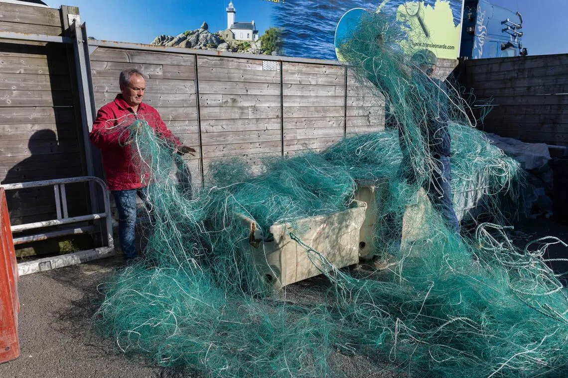 French charity association Kernic Solidarites member in charge of logistic Christian Abaziou (right) and its president Gerard Le Duff (left) sort out fishing nets to be sent to Ukraine.