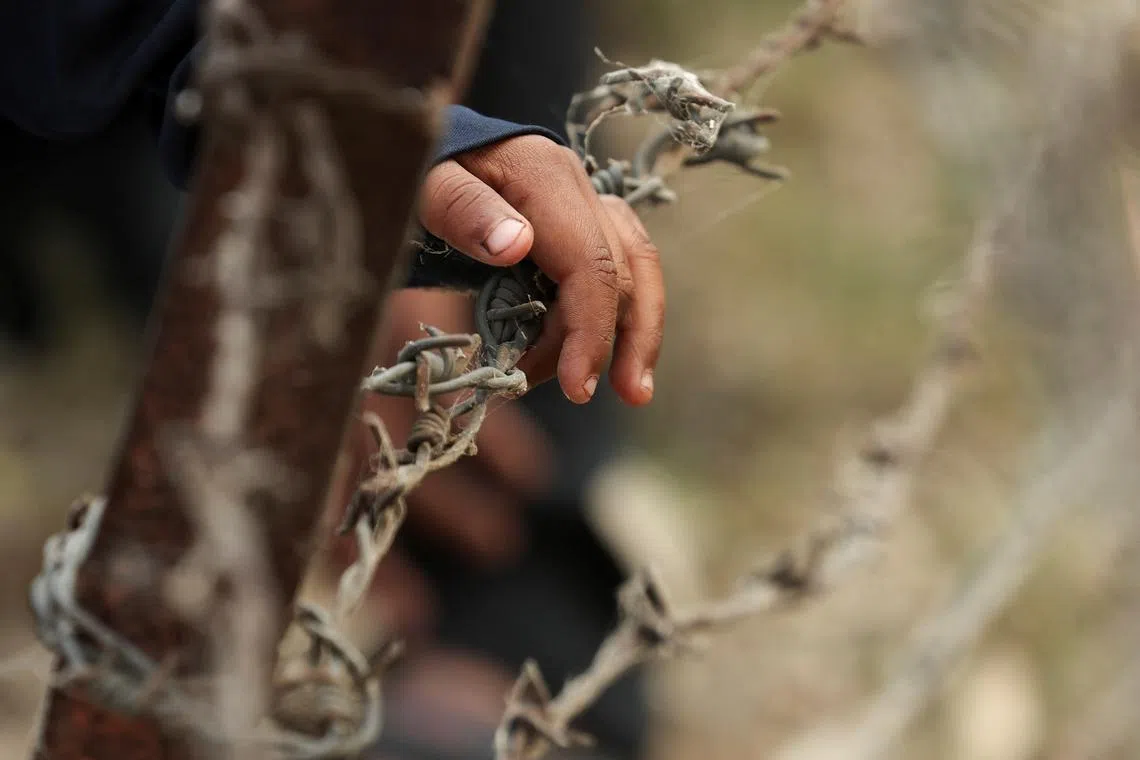 A child from Pakistan places his hand on barbed wire as he waits to go to Pakistan at the Attari-Wagah border crossing, after India revoked visas and suspended visa services to Pakistani citizens, following an attack on tourists near Pahalgam in south Kashmir, near Amritsar, India May 1, 2025. REUTERS/Francis Mascarenhas