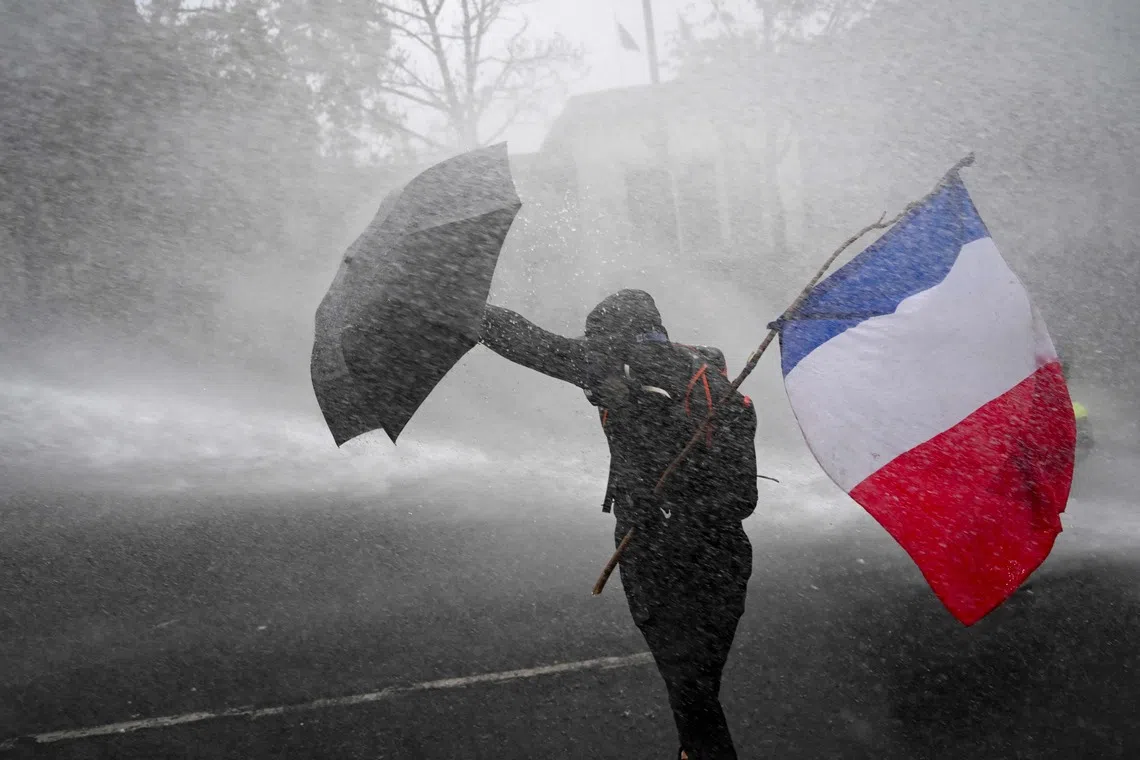 A flag-waving French protester holding off police water cannon during protests on Oct 24. Marine Le Pen is likely to come to power next year, propelled by widespread discontent against the centrist government.
