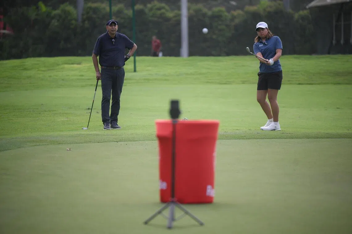 The Straits Times Assistant Sports Editor Rohit Brijnath (left) watches as Singaporean professional golfer Shannon Tan chips a ball during a chipping challenge at Sentosa Golf Club on Feb 21, 2026.