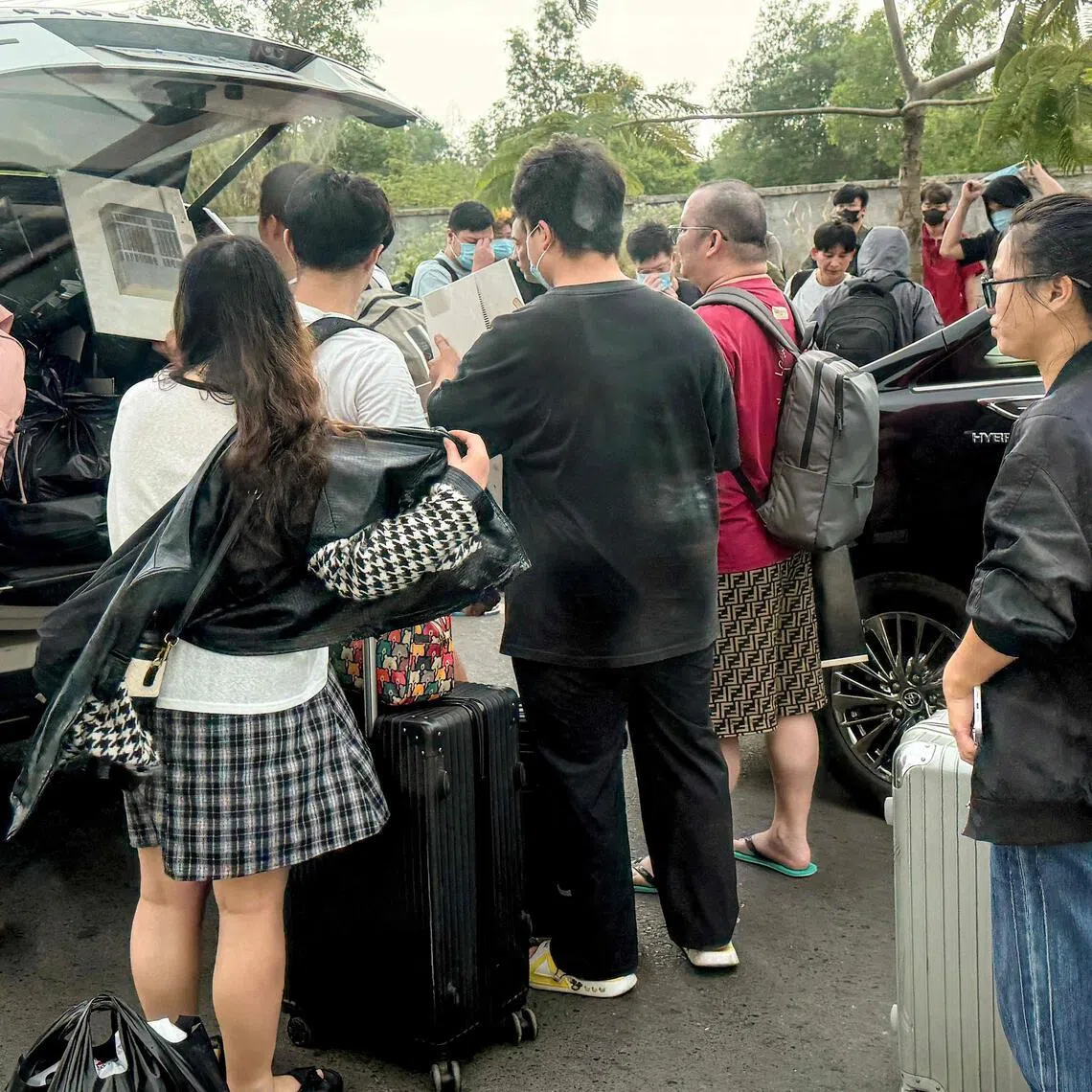 Workers load their luggage into waiting vehicles after walking out of a suspected scam centre compound in Sihanoukville on Jan 15.