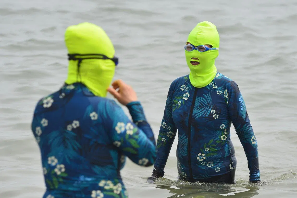 This photo taken on June 24, 2023 shows women clad in facekinis cooling off in the water amid hot weather in Qingdao, in China's eastern Shandong province. (Photo by AFP) / China OUT
