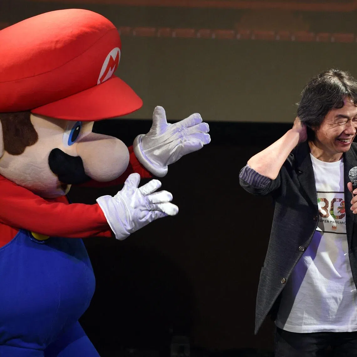 Nintendo game creator Shigeru Miyamoto reacting while standing with character Super Mario on Sept 13, 2015.