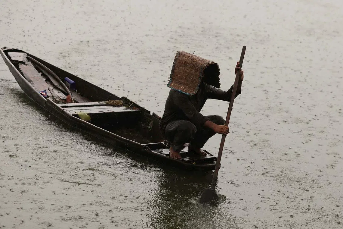 A worker removing weeds from the waters of Dal Lake during rain in Srinagar, India, Aug 18, 2025. 