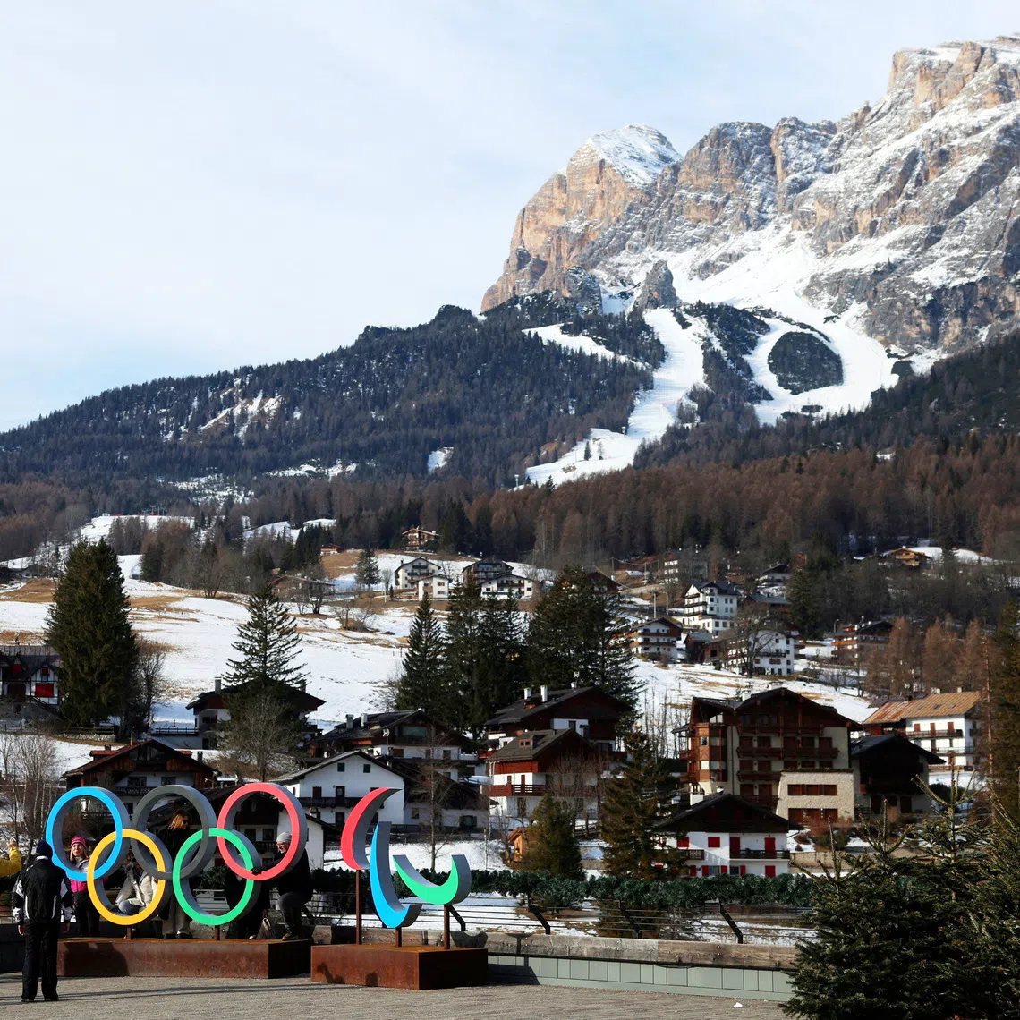 FILE PHOTO: People pose for a picture in front of the Olympic rings and Olympia delle Tofane track, which will host the women alpine skiing competition part of the Milano Cortina Winter Olympic Games 2026, in Cortina, Italy, January 24, 2025. REUTERS/Claudia Greco/File Photo