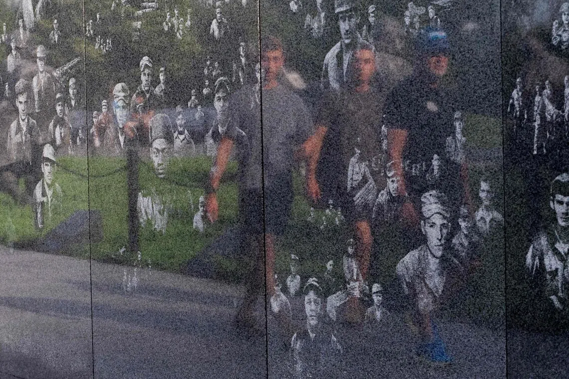 Three men walking past a remembrance wall at the Korea War Memorial at the National Mall ahead of Memorial Day in Washington, DC on May 26, 2024. 