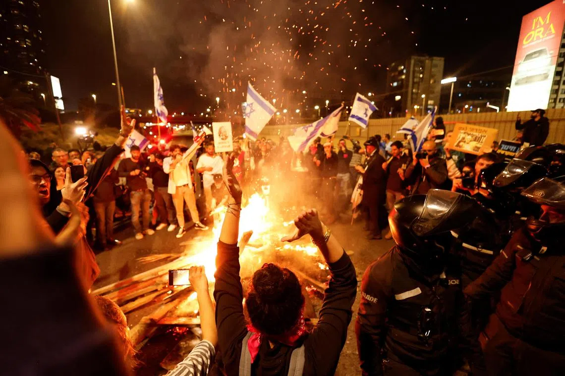 People and police stand next to a bonfire on a road during a protest against Israel's Prime Minister Benjamin Netanyahu's new right-wing coalition and its proposed judicial changes in Tel Aviv on Feb 25. 