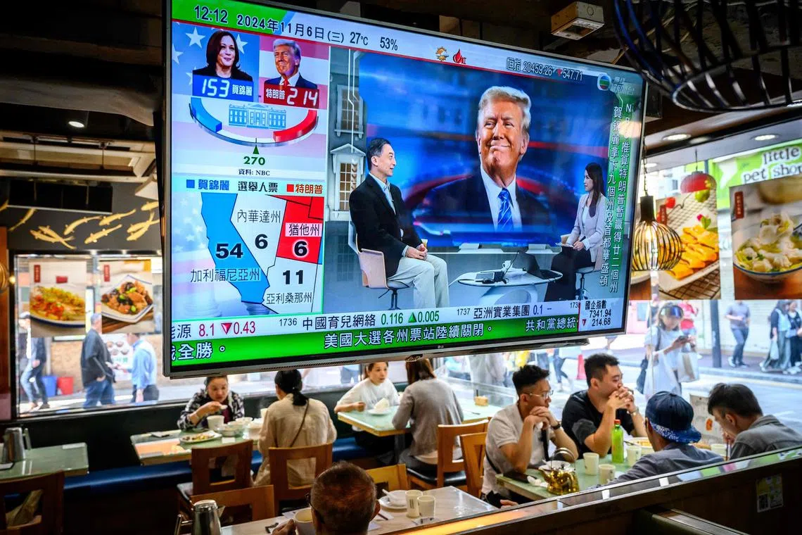 TOPSHOT - A TV screen showing preliminary results about the US elections hangs  in a restaurant in Hong Kong on November 6, 2024. White House rivals Kamala Harris and Donald Trump racked up early wins, as the first key polls closed in one of the tightest and most volatile presidential elections in US history. (Photo by Mladen ANTONOV / AFP)