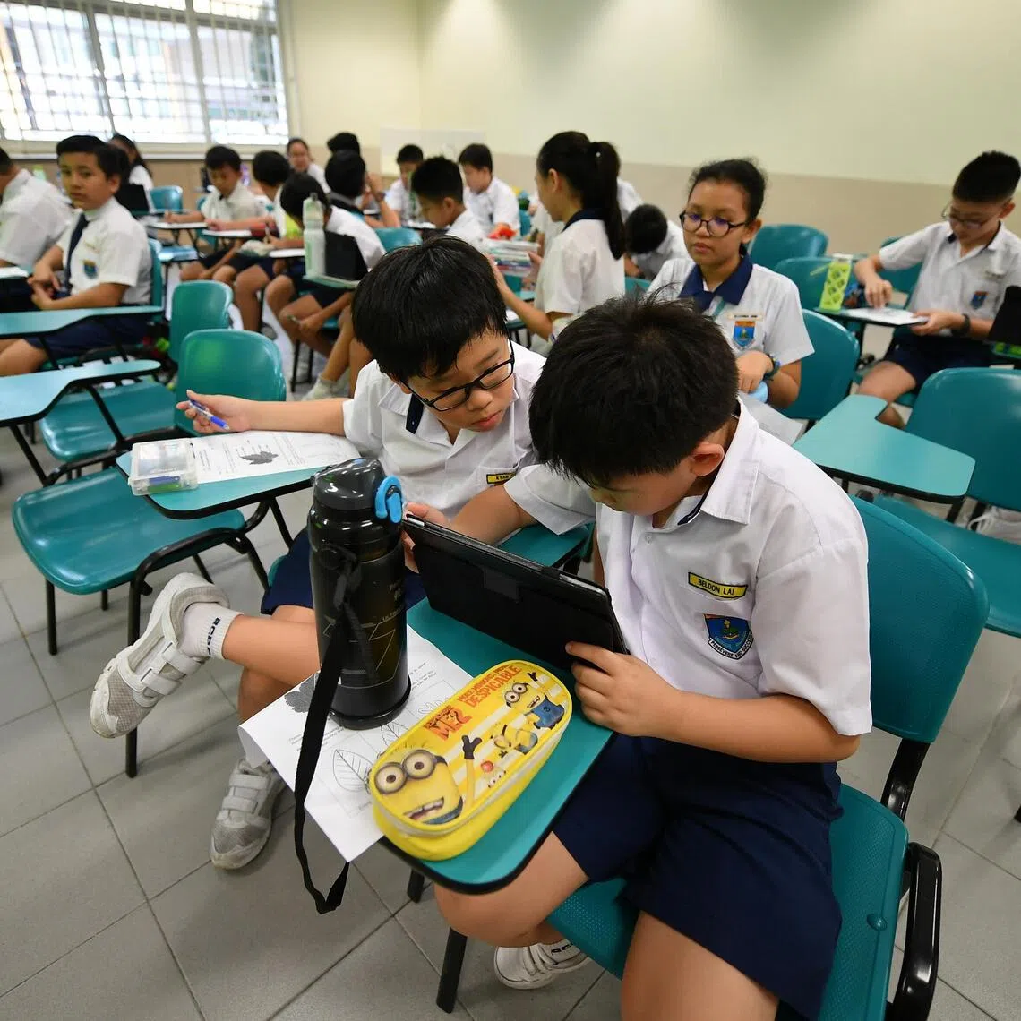 Primary 4 pupils Kyan Phua (bottom left) and Beldon Lai (bottom right) reading information about teh different parts of a plant via an app during their lesson on plant diversity at Bedok Green Primary School on October 26, 2018. 