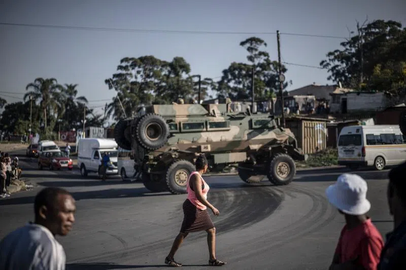 Pedestrians walking past an armoured military vehicle patrolling a looted area in Durban, on July 1, 2026.