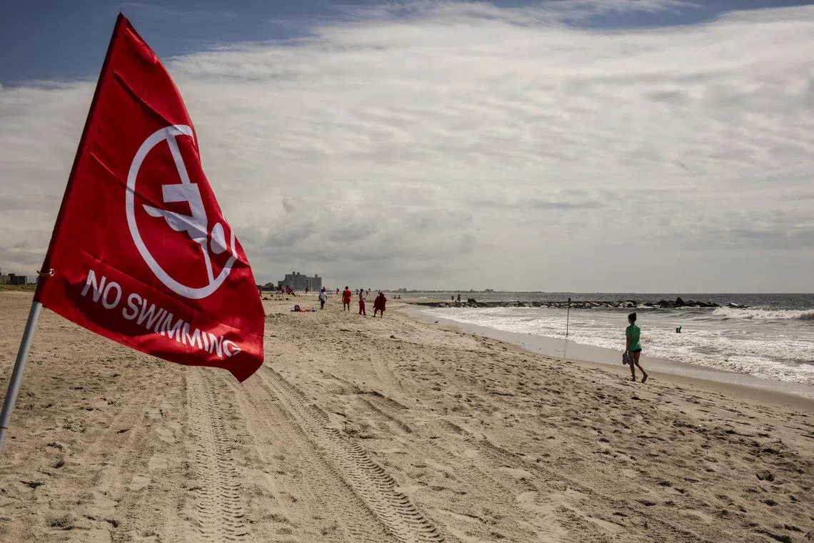 A flag warns against swimming the day after a swimmer was bitten by a shark at Rockaway Beach in New York, Aug. 8, 2023. A 50-year-old woman was bitten by a shark Monday afternoon at Rockaway Beach, the authorities said, in what appears to have been the first confirmed shark bite in New York City in decades. (Bryan Anselm/The New York Times)