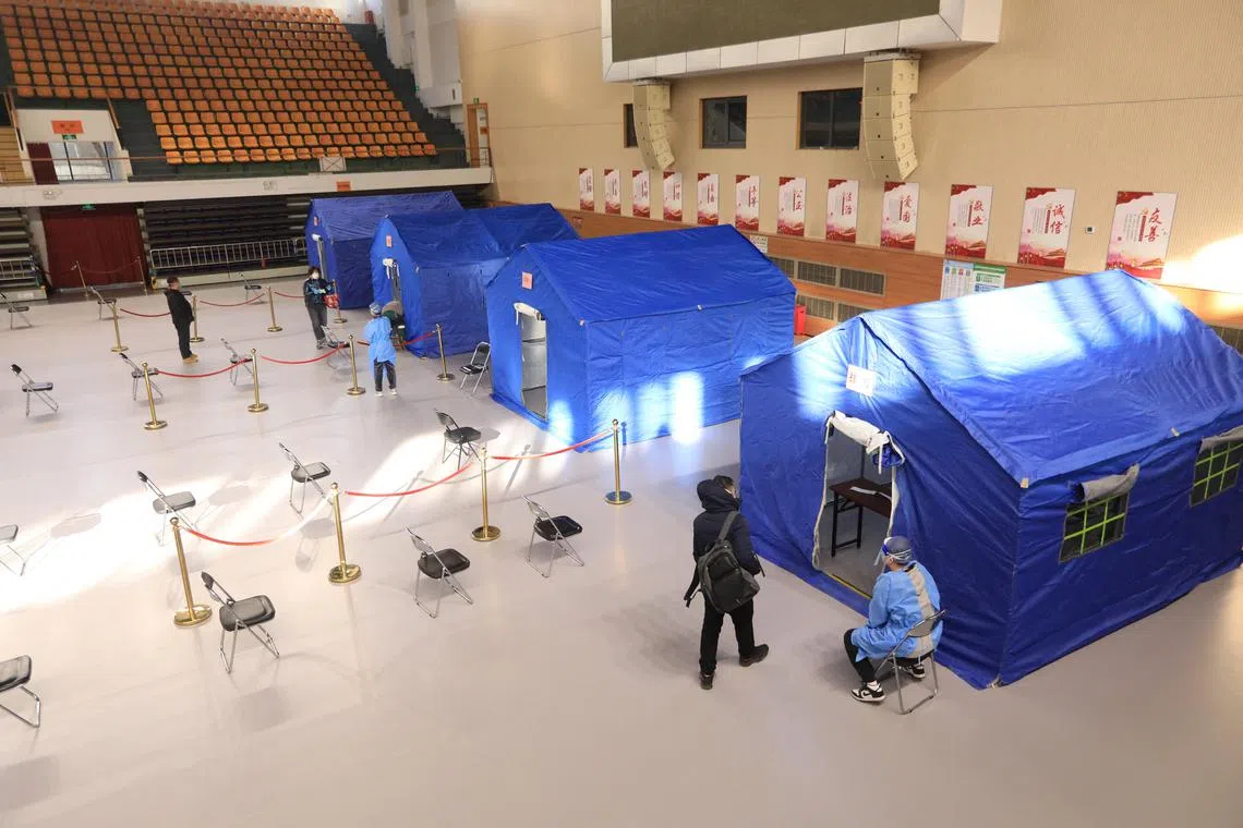 People line up at a makeshift fever clinic set up inside a stadium in Beijing, on Dec 14, 2022.