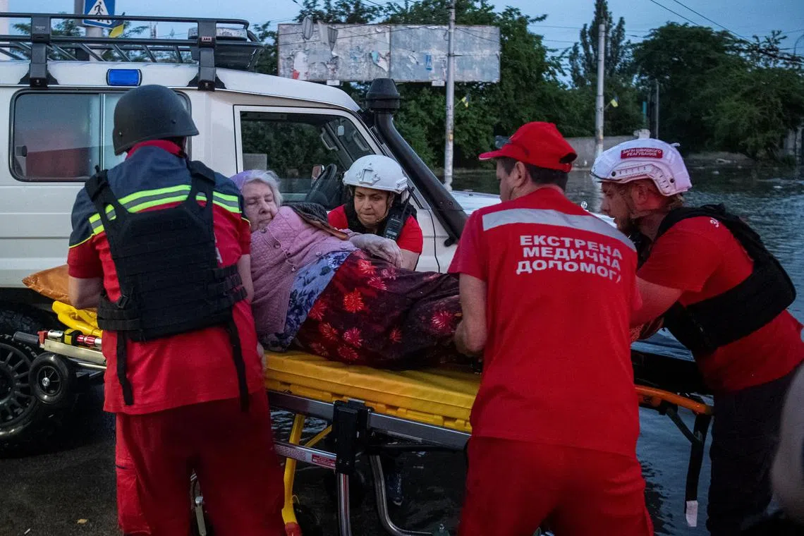 Red Cross volunteers evacuate an elderly woman from a flooded area in Ukraine's Kherson, after a major dam breach.