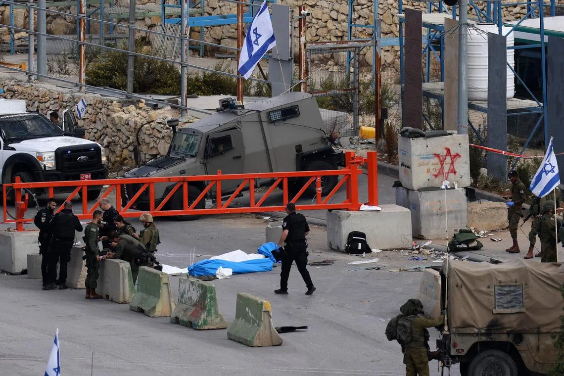 Israeli security forces stand near the bodies of two Palestinian men at a checkpoint in the northern entrance of the West Bank city of Hebron on Nov 17. Palestinian detainees and officials say Israel has ramped up arrests in the occupied West Bank and East Jerusalem the wake of the Oct 7 Hamas attacks.