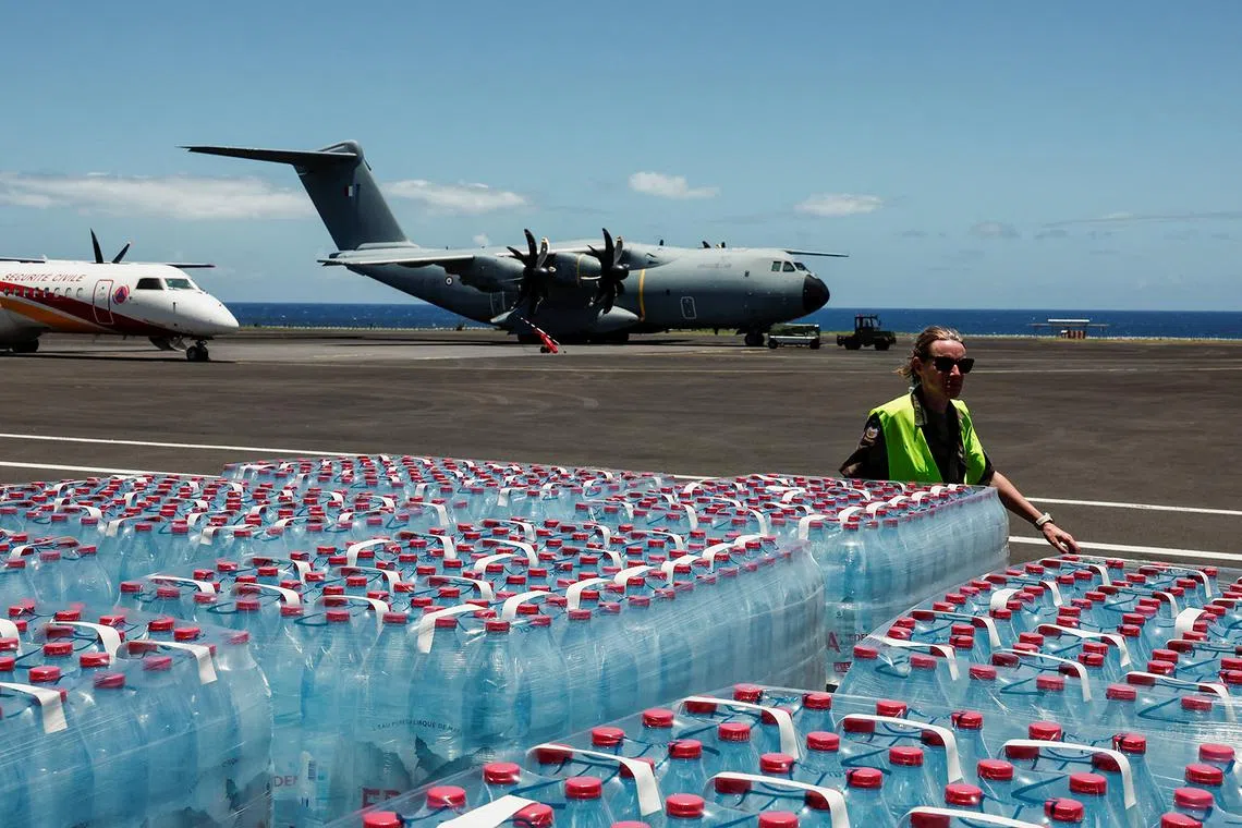 A member of the French military walking next to supplies to be transported to Mayotte, in the aftermath of Cyclone Chido, at a military airbase in Sainte Marie, Reunion Island, France, on Dec 17, 2024. 