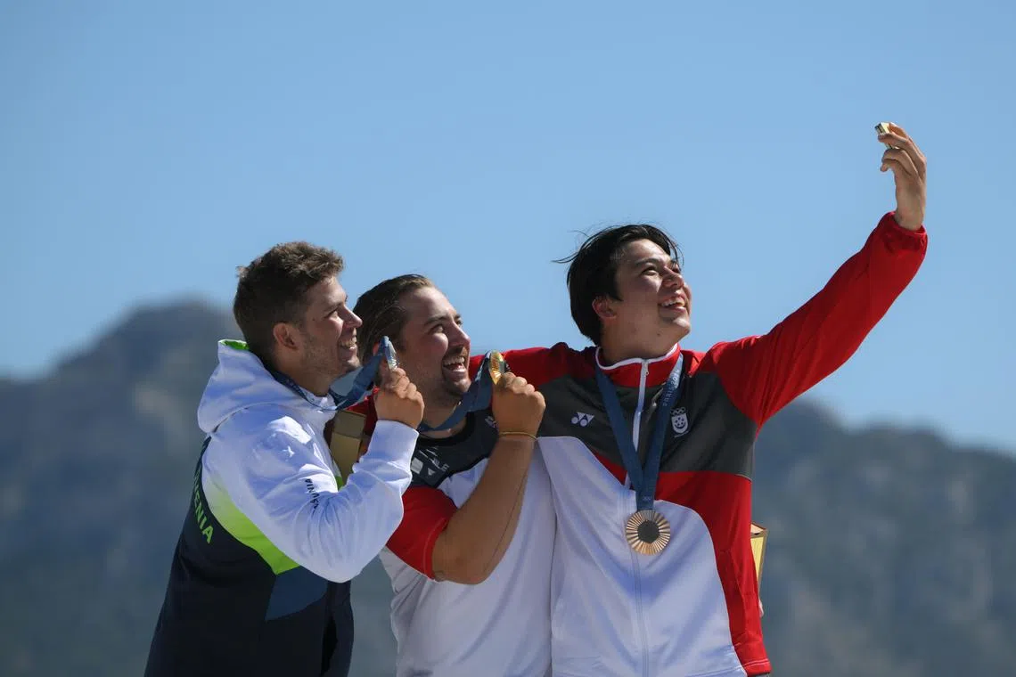 From left: silver medalist Toni Vodisek from Slovenia, gold medalist Valentin Bontus from Austria, and bronze medalist Maximilian Maeder from Singapore, after the Paris 2024 Olympics men’s kite final at the Marseille Marina on August 9.