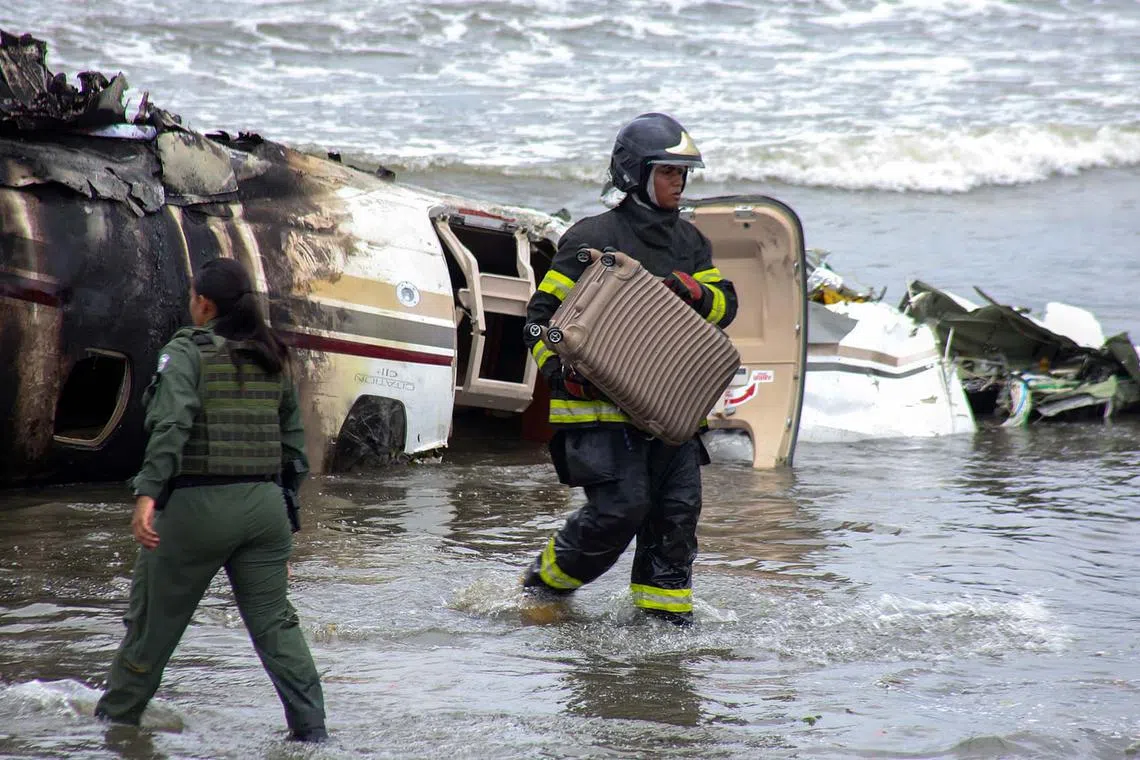 A rescue team worker carrying a suitcase recovered from a private plane that exploded and crashed into the Cruzeiro beach while attempting to take off from the Ubatuba airport, in Ubatuba, Sao Paulo state, Brazil, on Jan 9, 2025. According to Ubatuba City Hall, one person is dead and four other were injured. 