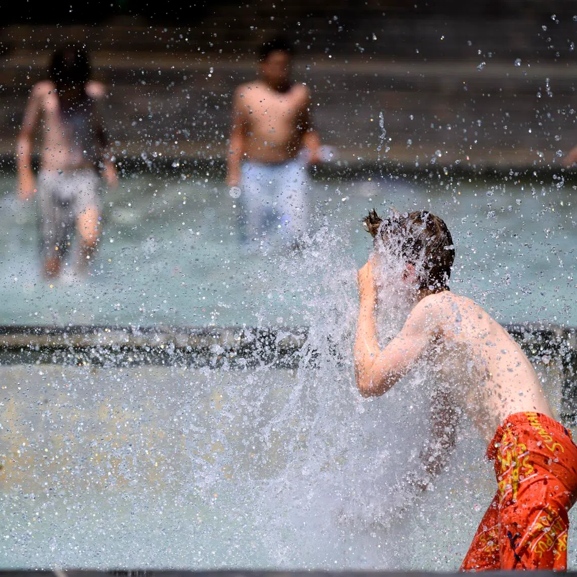 Children cool off by playing at a public fountain in Milan Park during a heat wave in Lausanne, Switzerland.
