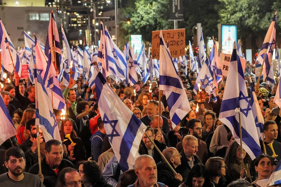 Demonstrators march with torches and with Israeli national flags during a protest against the government's controversial judicial reform Bill in Tel Aviv on March 9, 2023. 