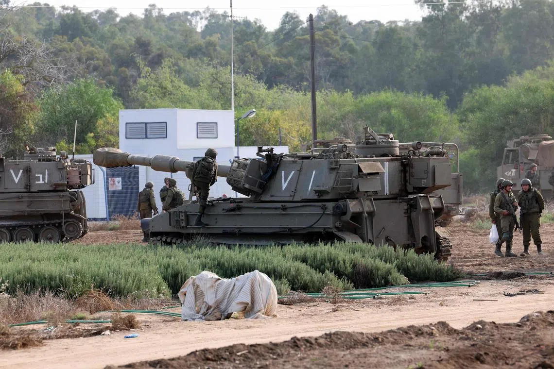 Israeli troops gathering with armoured vehicles at an undisclosed location on the border with the Gaza Strip on Oct 8.