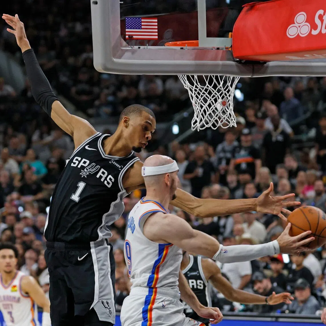 Alex Caruso of the Oklahoma City Thunder looks for a pass against Victor Wembanyama of the San Antonio Spurs in the third quarter of Game 6.