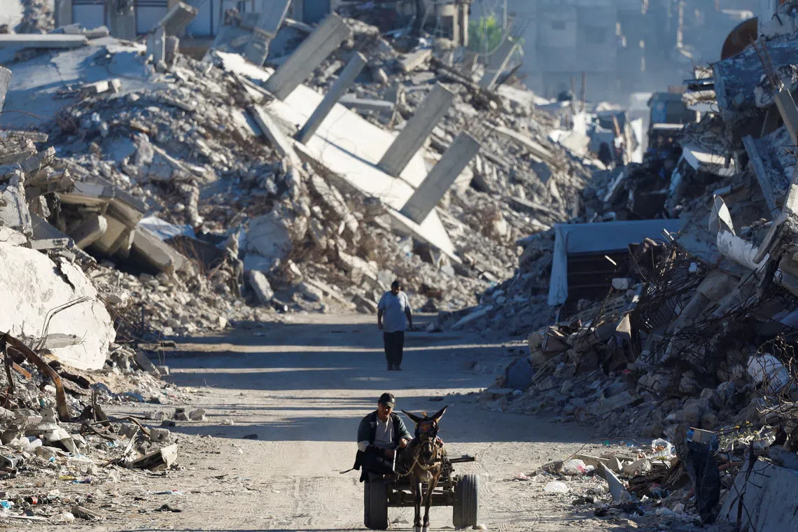 A Palestinian man rides a cart pulled by a donkey amid the rubble of buildings destroyed during the war, in Gaza City, Oct 7.