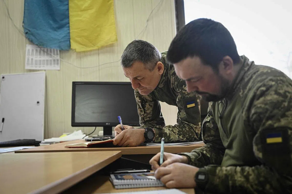 Ukrainian servicemen Ihor Soldatenko (L), 50, and Yuriy Kalmutskiy (C), 36, attending a lesson of English at a military facility in Kyiv.