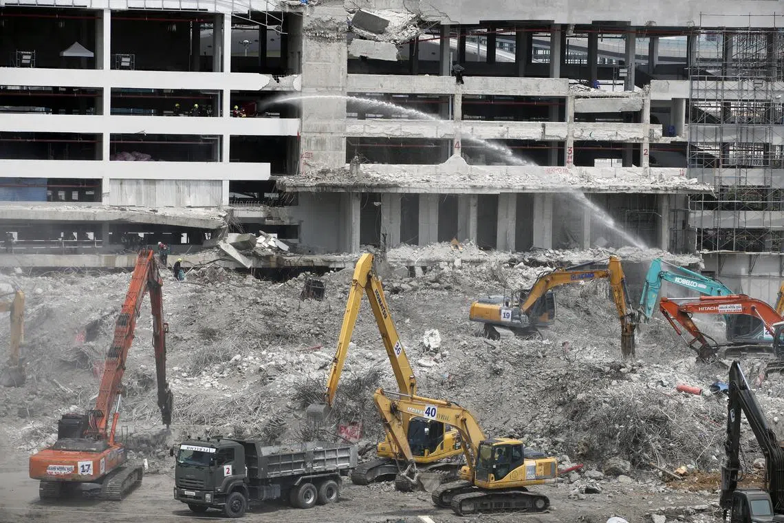 Rescue workers remove debris at the site of a building in Bangkok that collapsed during a massive quake on March 28.