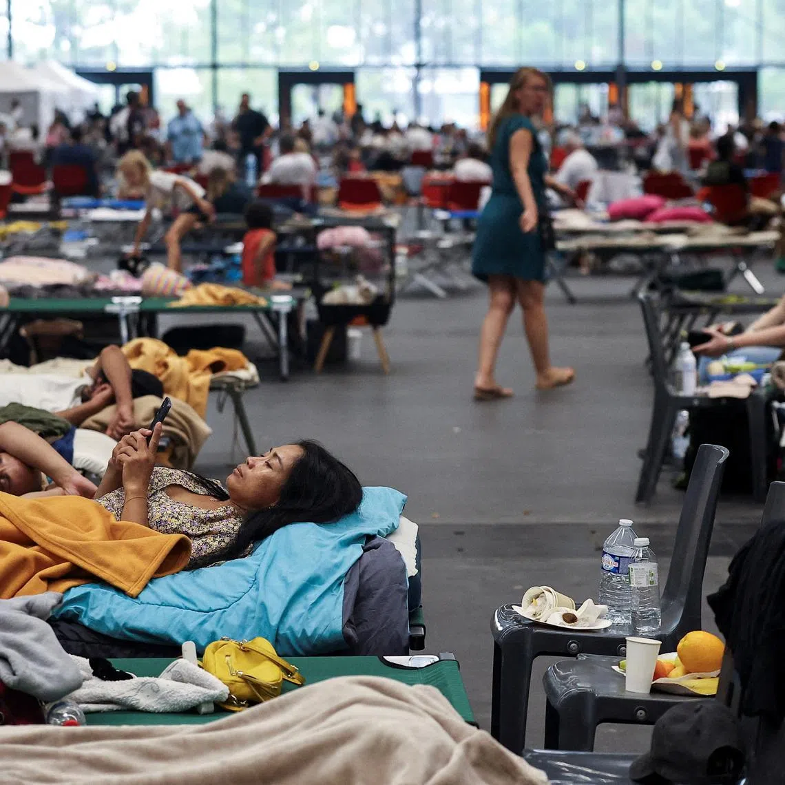 A woman looks at her phone at the Bordeaux-Lac Exhibition Centre, which has been turned into a shelter for people displaced by a wildfire burning nearby amid worsening drought conditions following a heatwave and water shortages across much of France, in Bordeaux, France, July 25, 2026. REUTERS/Manon Cruz
