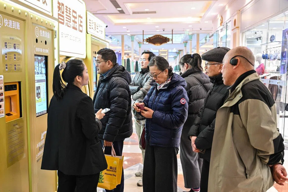 Customers wait to sell their gold jewelry in a Smart Gold Store Machine placed in a shopping in Shanghai on January 29, 2026. Dozens of people crowded around an automated gold recycling machine at a Shanghai mall, hoping to melt down family heirlooms for cash as prices of the precious metal hit record highs. (Photo by Hector RETAMAL / AFP) / TO GO WITH: China-economy-gold, by Jing Xuan Teng