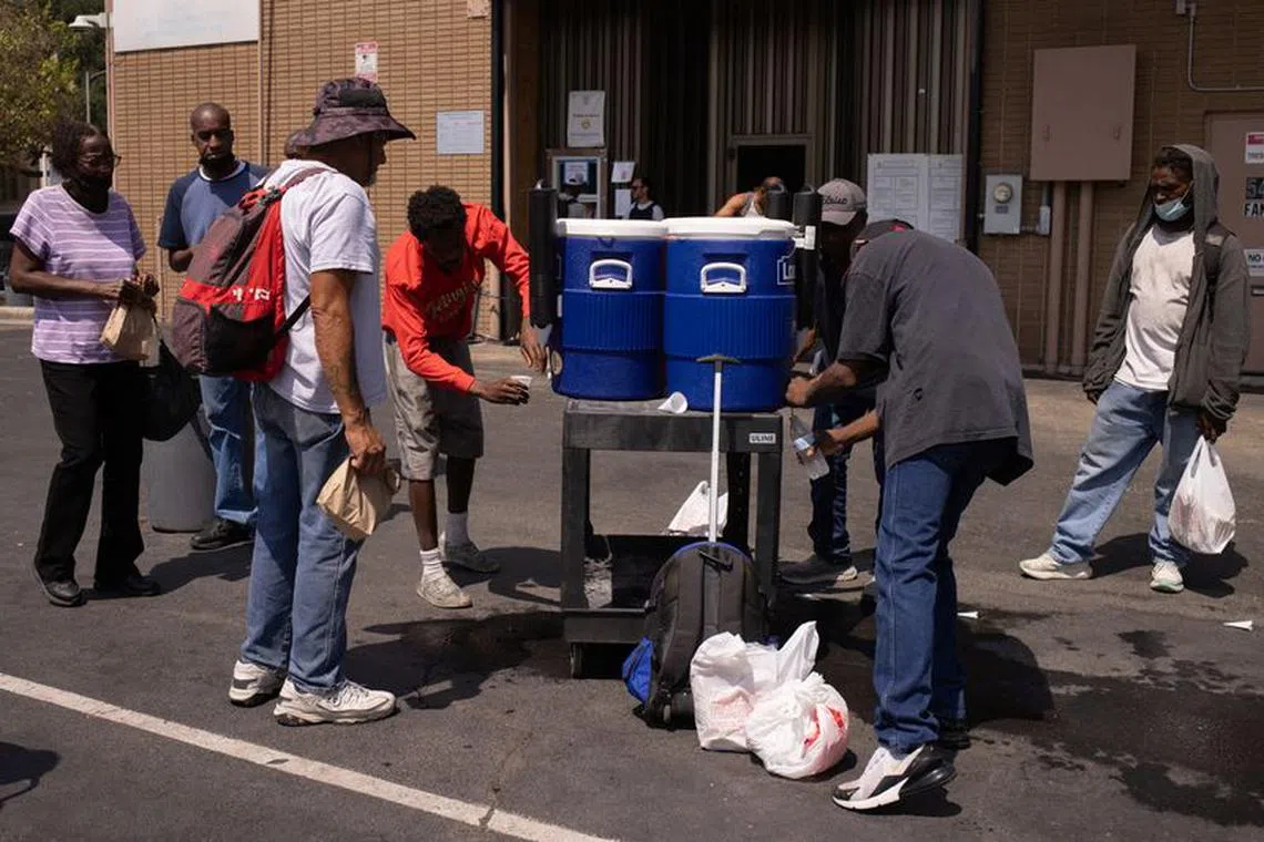 FILE PHOTO: People drink cold water outside the Emergency Aid Coalition during a heat wave in Houston, Texas, U.S., August 25, 2023.  REUTERS/Adrees Latif/File Photo