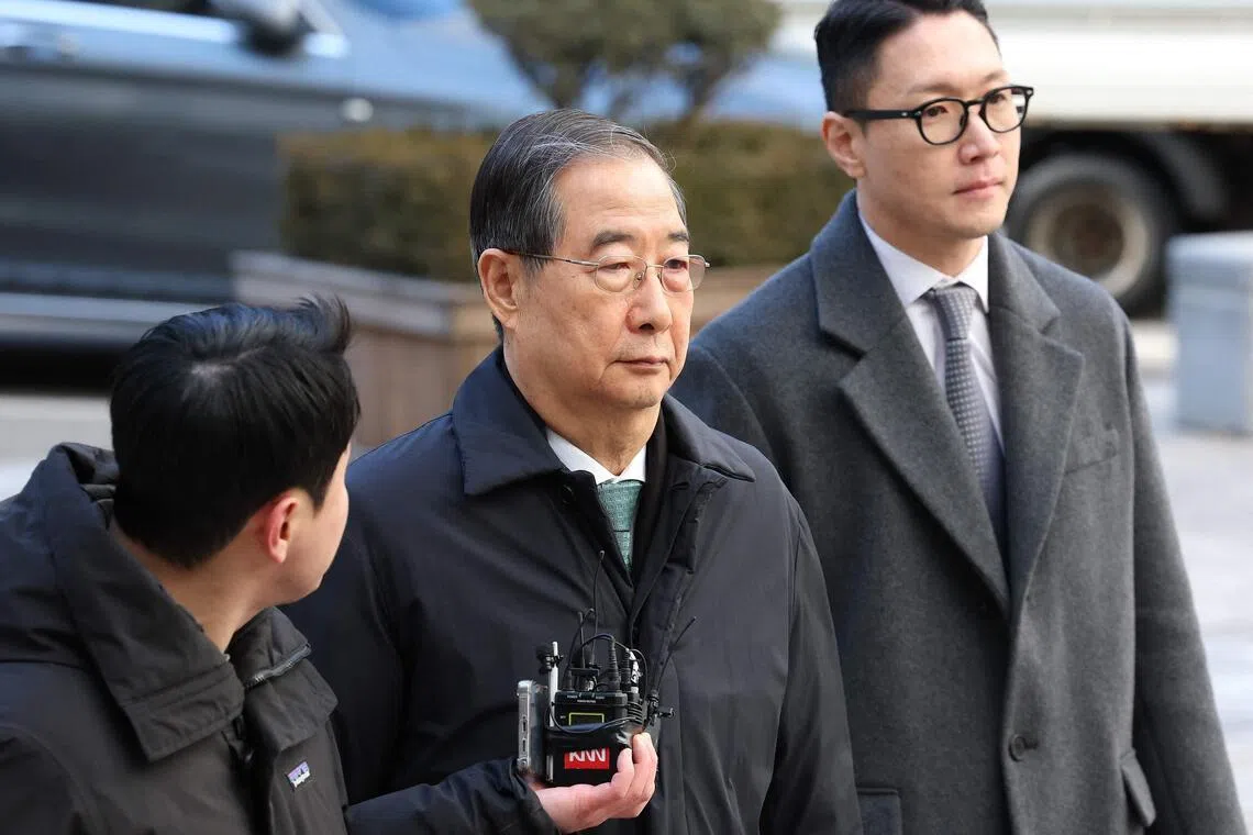 Former South Korean prime minister Han Duck-soo (centre) arrives at the Seoul Central District Court for his first sentencing trial in the insurrection case in Seoul on Jan  21, 2026.