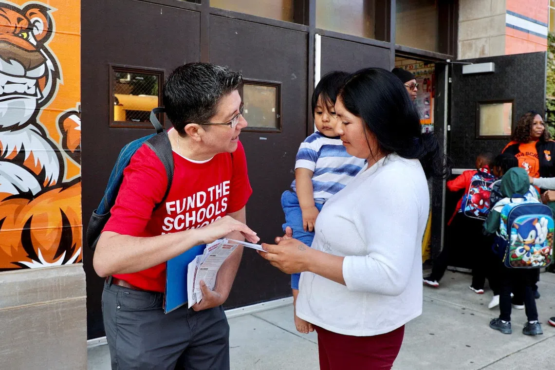 A teacher handing out a leaflet to a parent outside Nash Elementary School in Chicago on Sept 4.
