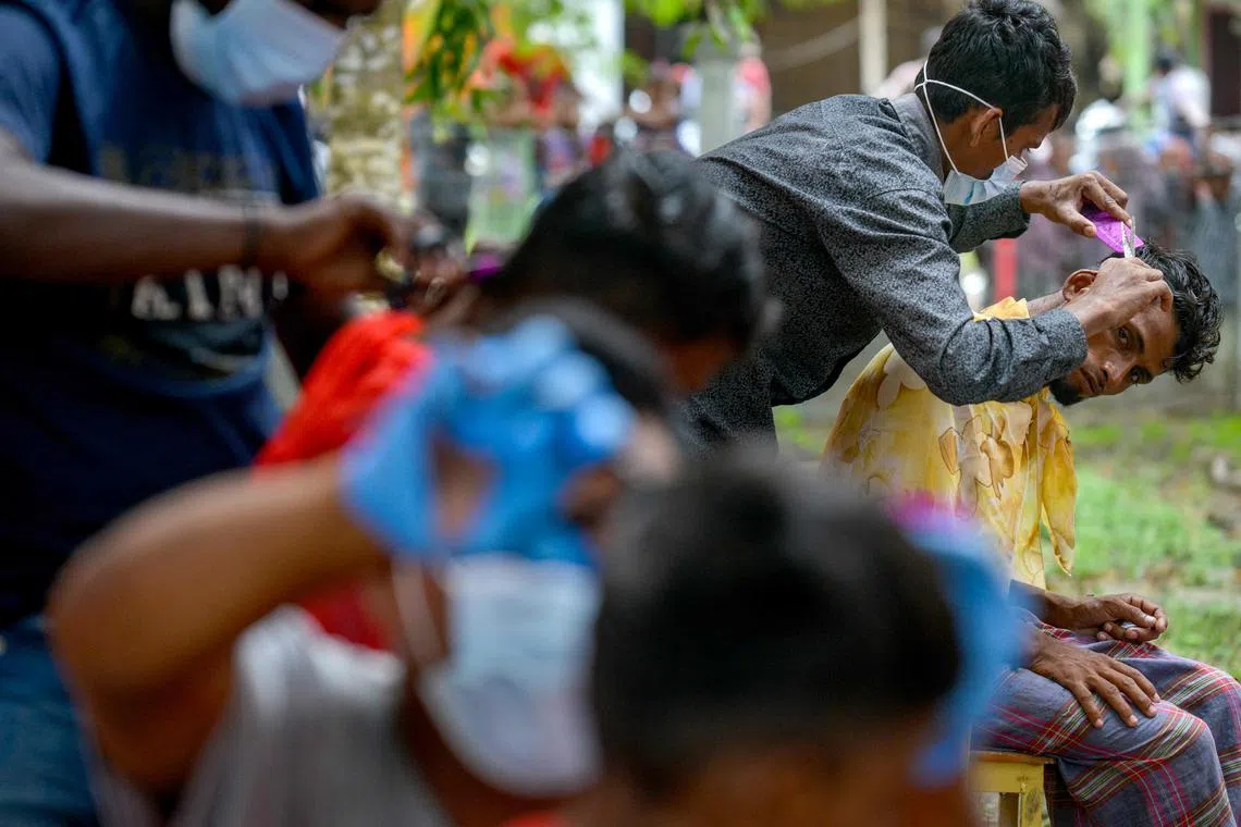 Rohingya refugees get their haircuts at a temporary shelter after arriving by boat in Laweueng, Aceh province on December 27, 2022. 