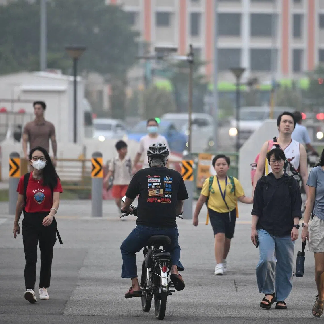 Pedestrians wearing face masks and crossing Tampines Avenue 1 towards Block 803 Tampines Avenue 4 at 7am on Oct 16.