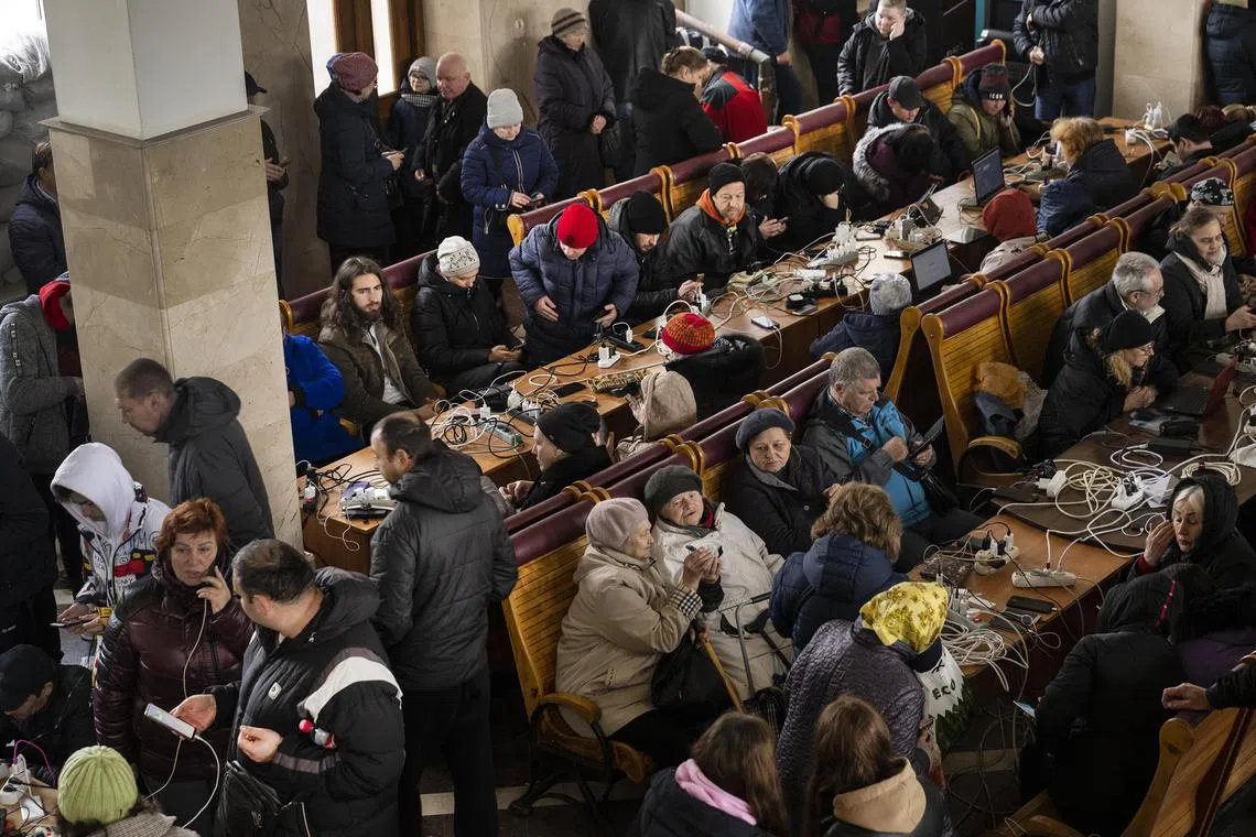 Residents charge their phones at the train station, as the city's critical infrastructure were destroyed, in Kherson on Nov 19, 2022. 