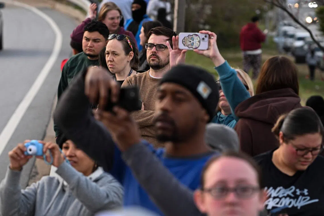Onlookers looking at the Francis Scott Key Bridge that collapsed after being hit by the container ship Dali in Baltimore, Maryland, on March 26, 2024. 